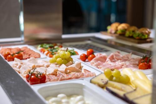 a buffet line with meats and tomatoes and other foods at Hi Hotels Torbole - Heated Outdoor Pool & Spa in Nago-Torbole