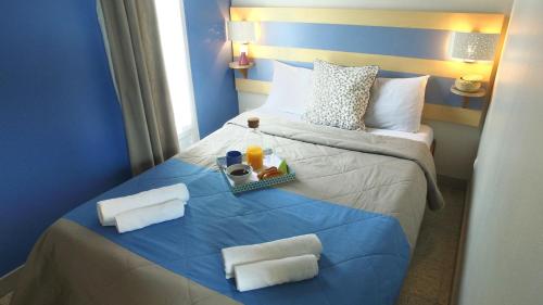 Una habitación de hotel con una cama con una bandeja de comida encima. en VVF Golfe du Morbihan Sarzeau Arzon, en Sarzeau
