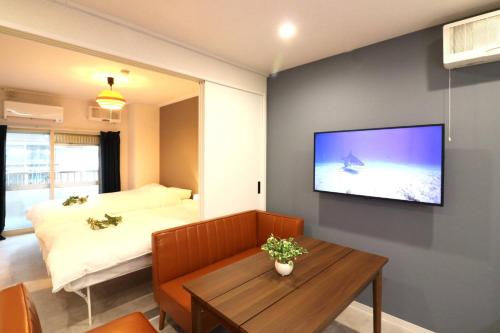 a room with a bed and a television on a wall at Shin Osaka Grand Heights SG31 in Osaka