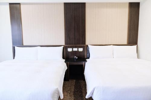 two beds in a hotel room with white sheets at YUAI FU HAO Hotel in Taichung