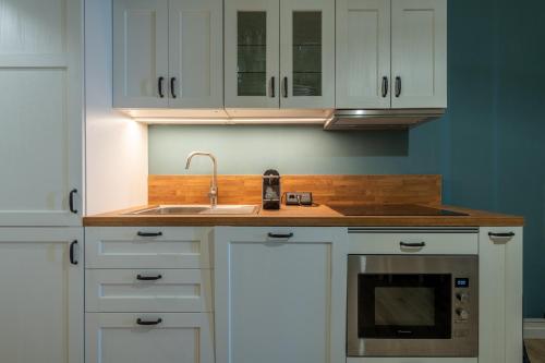 une cuisine avec des armoires blanches et un évier dans l'établissement Graziella - appartement en front de mer, à Mers-les-Bains