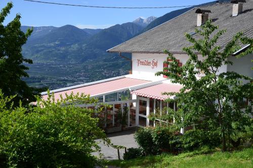 a white building with mountains in the background at Garni Praidlerhof in Tirolo