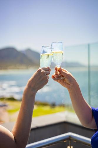 a woman holding a glass of white wine at Ocean Family Deluxe, Hermanus Waterfront - Apt 2 in Hermanus