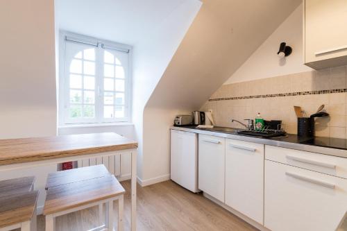 une cuisine avec des armoires blanches et une fenêtre dans l'établissement Studio des Halles - Charmant - Port - Wifi, à Vannes
