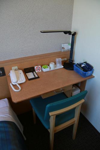 a desk in a hotel room with a phone on it at Hotel Plaza Arakawaoki in Tsuchiura