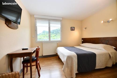 une chambre avec un lit, un bureau et une télévision dans l'établissement bar hotel restaurant des voyageurs, à Le Falgoux