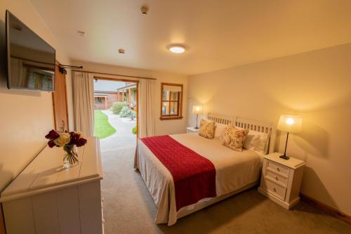 a bedroom with a bed and a sliding glass door at Wanaka Homestead Lodge & Cottages in Wanaka