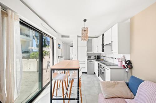 une cuisine avec des armoires blanches et une table dans l'établissement Maisonnette Saona vue mer plages 800m WiFi CLiM PK By HC, à Carqueiranne