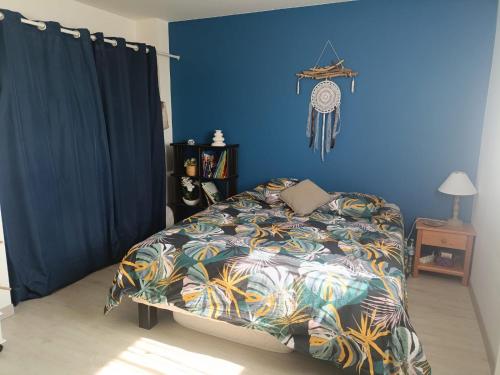 a bedroom with a bed with a blue wall at L'Air de Caen in Esquay-Notre-Dame