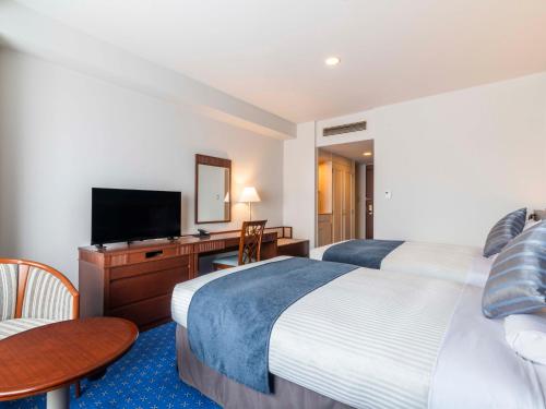 a hotel room with two beds and a flat screen tv at ART HOTEL Kashima Central in Kamisu
