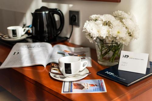 a table with a vase of flowers and a cup of coffee at Hotel de Francia y París in Cádiz