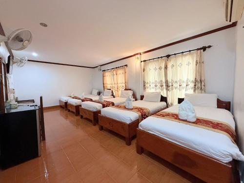 a room with four beds and a flat screen tv at Vangvieng Sisavang Mountain View Hotel in Vang Vieng