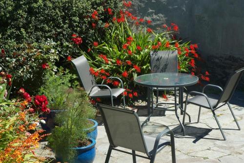 a group of chairs and a table and some flowers at Cosy Seaside Cottage Baltimore in Ballylinchy