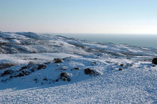 a snow covered mountain with the ocean in the background at Cosy Seaside Cottage Baltimore in Ballylinchy