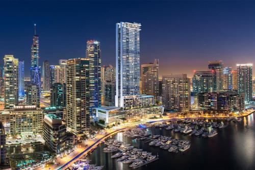 a city skyline at night with boats in the water at 1BR Gem with Stunning Marina Views, Close to Metro in Dubai