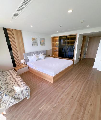 a bedroom with a large white bed and wooden floors at Flamingo Hai Tien in Hoằng Hóa