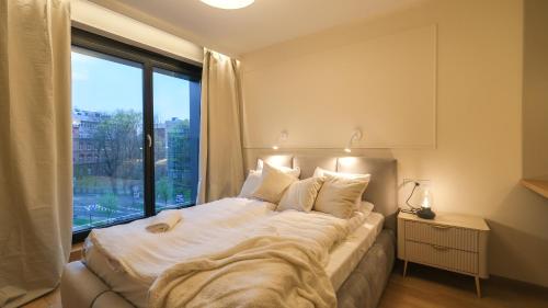 Un dormitorio con una cama grande con una ventana grande. en Angel's apartments - by Hosty, en Cracovia