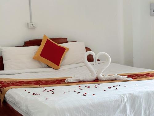 two white swans sitting on a bed with confetti at Vangvieng Sisavang Mountain View Hotel in Vang Vieng
