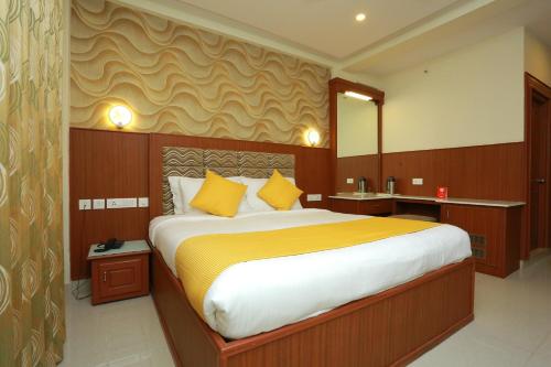 a bedroom with a large bed with yellow pillows at Super Capital O Kovilakam Residency in Trichūr
