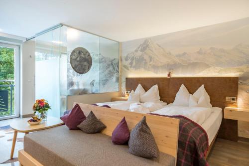 a bedroom with a large bed with purple pillows at AllgäuHotel Tanneck in Fischen