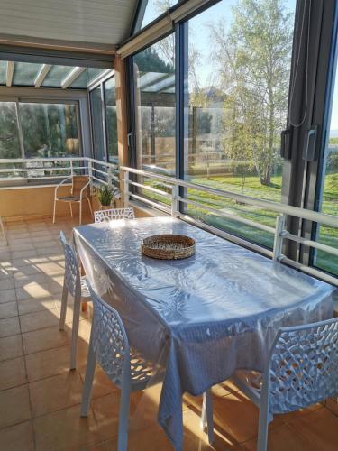 une salle à manger avec une table, des chaises et des fenêtres dans l'établissement CAP Baie Malo, à Hirel