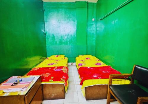 two beds in a room with a green wall at Hotel Al Makka Dhaka in Dhaka