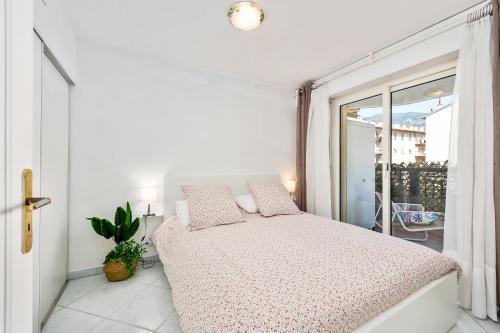 une chambre blanche avec un lit et un balcon dans l'établissement DATURAS - Agréable 2 pièces - Proche Mer - Menton Centre, à Menton