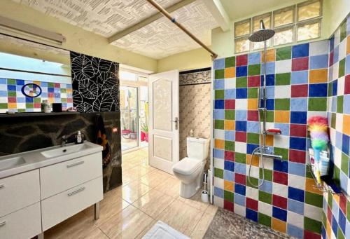 a bathroom with a toilet and a colorful tile wall at Casa Estrada in Caleta de Interián