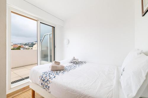 une chambre blanche avec un lit et une grande fenêtre dans l'établissement 904 - Rooftop in city center, beach 100m away, à Menton