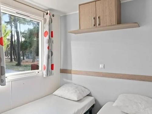 une petite chambre avec deux lits et une fenêtre dans l'établissement Camping Les Catalpas de Royan - Aquatique Vacances, à Saint-Georges-de-Didonne