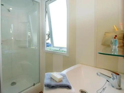 une salle de bain blanche avec un lavabo et une douche dans l'établissement Camping Les Catalpas de Royan - Aquatique Vacances, à Saint-Georges-de-Didonne
