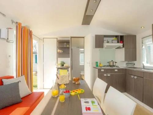 un salon avec une table et une cuisine dans l'établissement Camping Les Catalpas de Royan - Aquatique Vacances, à Saint-Georges-de-Didonne