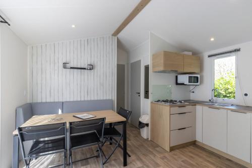 une cuisine et une salle à manger avec une table et des chaises dans l'établissement Mobilhome Malaga Clim Trio, à Bouzic