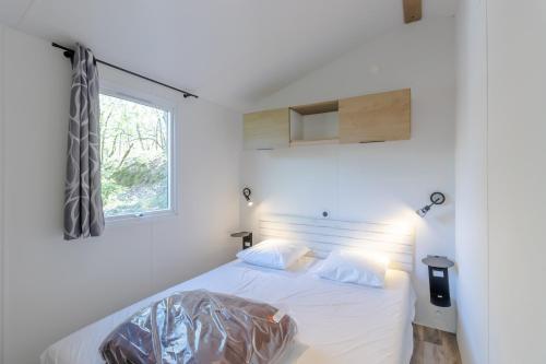 un lit blanc dans une chambre avec une fenêtre dans l'établissement Mobilhome Malaga Clim Trio, à Bouzic