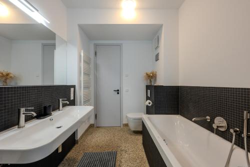 a bathroom with two sinks and a tub and a toilet at Marina Maisonette Seeblick mit Pool und Sauna in Bad Saarow