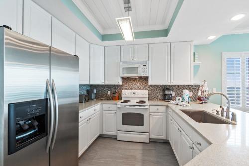 eine Küche mit weißen Schränken und einem Edelstahlkühlschrank in der Unterkunft San Carlos 1501 in Gulf Shores