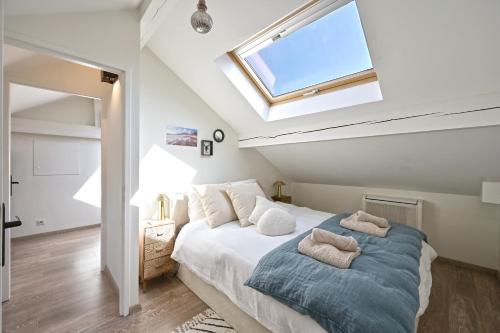 une chambre avec un grand lit avec une lucarne dans l'établissement Le Pamela - Appt climatisé, à Aix-les-Bains