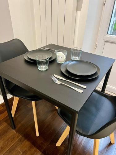 une table noire avec des assiettes et des verres dans l'établissement COSY IVRY charmant 2 pièces aux portes de Paris, à Ivry-sur-Seine