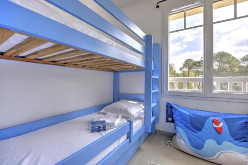 Cette chambre dispose de lits superposés bleus et d'une fenêtre. dans l'établissement Couleur Pyla - Avec piscine partagée, à La Teste-de-Buch