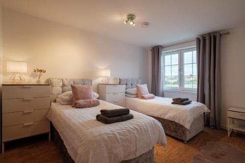 a bedroom with two beds and a window at Mackie Residence - SJA Stays - 3 Bed Apartment with parking in Westhill 