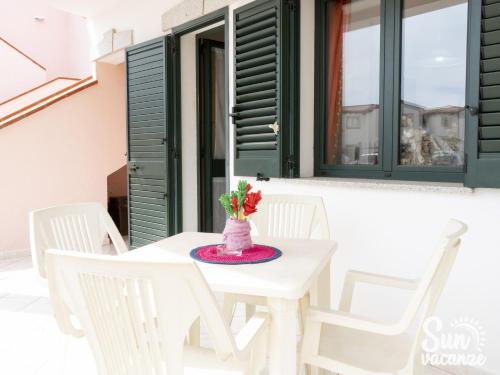 a white table with white chairs and a vase with flowers at Limpiddu in Limpiddu