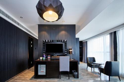 a living room with a television and a table and chairs at Orange Hotel Shanghai Hongkou Football Stadium Branch in Shanghai