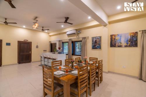 a dining room with a wooden table and chairs at StayVista at Leela Retreat with BBQ, Bonfire, Pool & Lawn in Sohna
