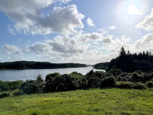 a view of a body of water with trees and clouds at Lake House Lough Atorick in Pollavogo
