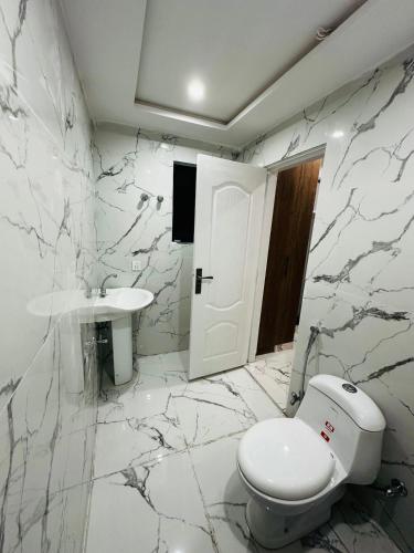 a white bathroom with a toilet and a sink at Urban Apartments in Sialkot