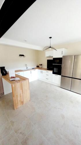 a large kitchen with white cabinets and a wooden table at Gîte Gournier's Sweet Home in Bas-en-Basset