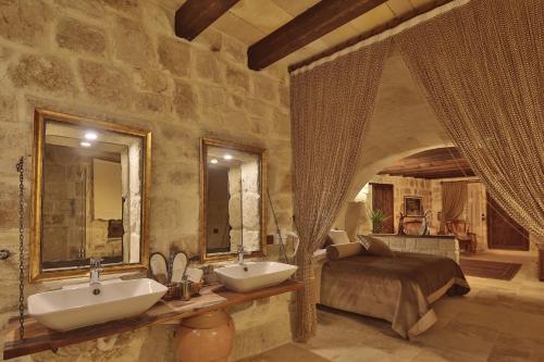 a bathroom with two sinks and a bed in a room at Asuwari Suites Cappadocia in Ürgüp