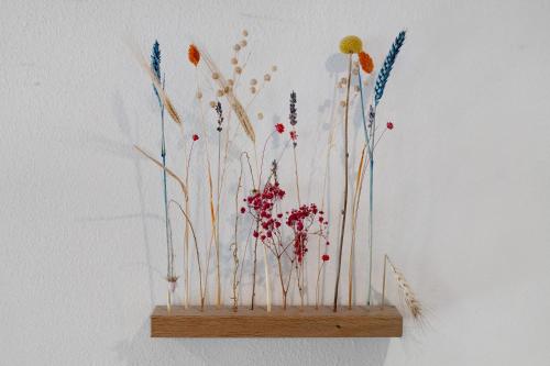 a wooden shelf with flowers on a wall at Müllerleile Hof in Haslach im Kinzigtal