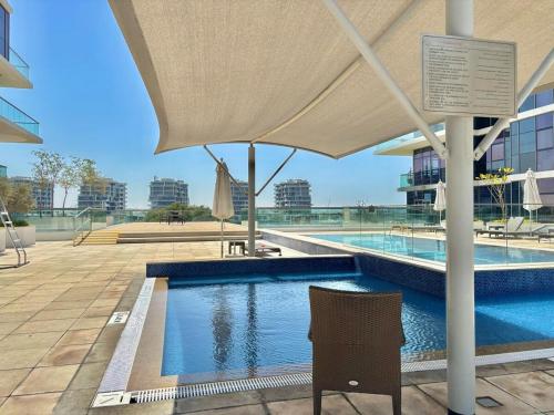 a swimming pool with a chair and an umbrella at FIRST CLASS Studio Urban Hideaway in Dubai