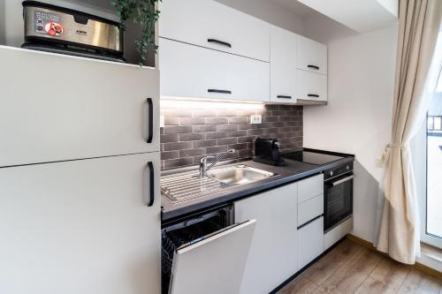 a kitchen with white cabinets and a sink at Skylark - Cairo Penthouse cu Jacuzzi si Vedere la Munte in Braşov